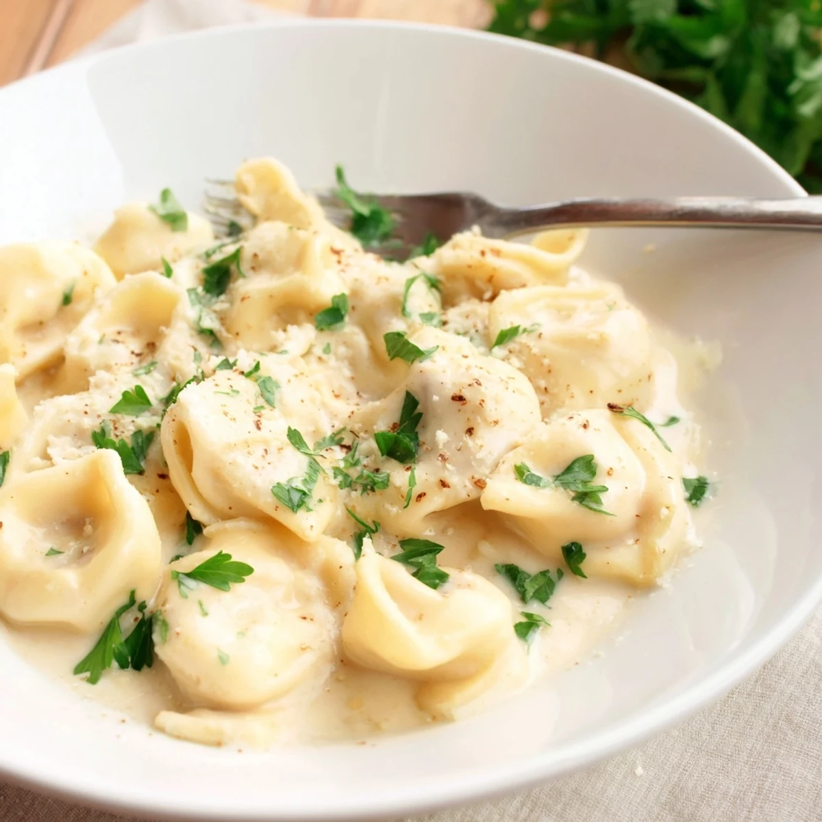 Bowl of tender chicken tortellini served in a savory light cream sauce garnish.