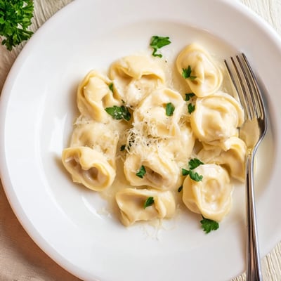 Close up of handmade chicken tortellini tossed with butter and shredded parmesan cheese.